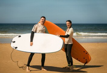 Family of surfers learning to surf in the Atlantic ocean. First surfing lesson. Amateur surfer. Surfing training. Photo for surfing school advertising on social media.