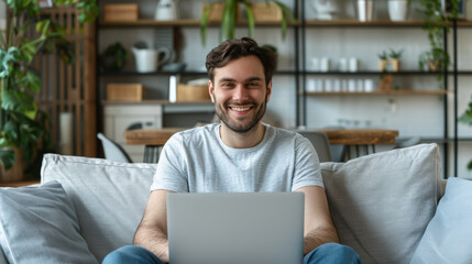 Happy young man working on laptop in modern home setting