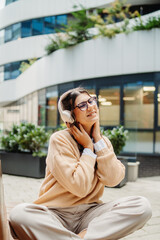 Young caucasian woman listening to music or audiobook outdoors
