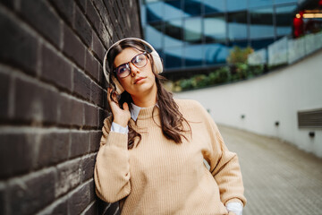 Fototapeta premium Young caucasian woman listening to music or audiobook outdoors