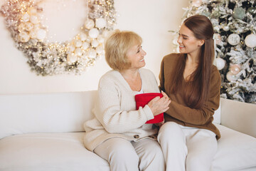 Obraz premium Warm Holiday Moment Between Grandmother and Granddaughter on Couch