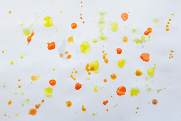 Drops of yellow and orange paint on a white sheet of paper, artist's studio. Creative background for your design or addition to illustrations.
