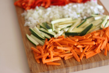 Chopped leek, red pepper, onion, zucchini and carrot on the chopping board. Cooking and meal prepping at home. Selective focus.