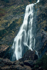 Obraz premium A waterfall is surrounded by rocks and trees in the mountains