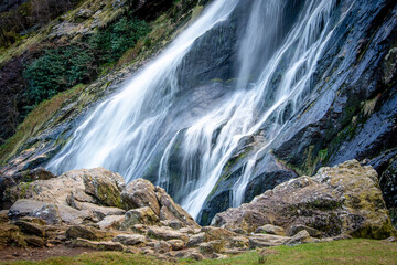 A waterfall surrounded by rocks and grass in a forest