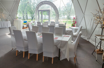 Inside of city cafe. Modern Cafe restaurant interior with white chairs around a round coffee table. Luxury restaurant interior. Empty tables at a restaurant. Modern white coffee shop interior.