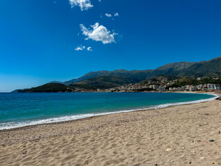Obraz premium Panoramic view of the picturesque coastline of coastal tourist town Himare, Vlore, Albania. Idyllic sand beach Potami with scenic vistas of majestic Ceraunian mountains. Summer vacation concept