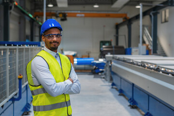 Production line engineer in a factory with yellow vest and blue helmet at work.