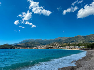 Panoramic view of the picturesque coastline of coastal tourist town Himare, Vlore, Albania. Idyllic sand beach Potami with scenic vistas of majestic Ceraunian mountains. Summer vacation concept