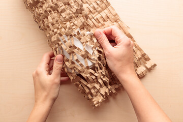 Brown Primary Color Honeycomb Wrapping Paper. Human packs a mug into a brown eco friendly reusable craft packing paper for moving or post delivery