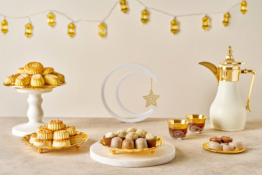 Assorted semolina maamoul or mamoul cookies , chocolate candy , awameh or lokma with dallah and ramadan decor fanous lights. Traditional arabic Eid al Adha, Eid al Fitr , Ramadan sweets