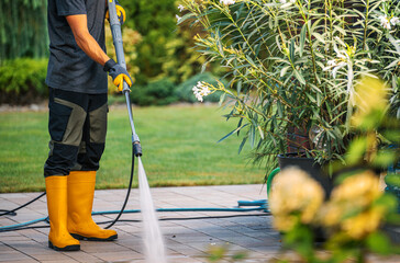 Person Cleaning Patio With Pressure Washer in a Garden During Sunny Day