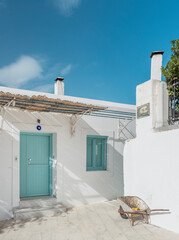 Discover the allure of Hydra's traditional architecture, characterized by whitewashed houses and colorful doors, bathed in bright sunlight against a clear blue sky.