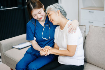 Fototapeta premium Asian caregiver doctor examine older patient woman therapist nurse at nursing home taking care of senior elderly woman sit on sofa.Medical service concept.