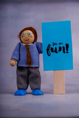 Wooden figure holding a motivational blue sign with positive vibes, representing optimism and...