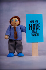 Wooden toy holding a blue sign with an encouraging message, conveying positivity and motivation in...