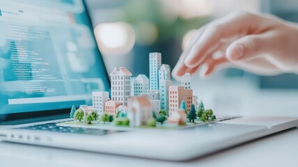 Obraz premium A hand interacts with a miniature cityscape placed on a laptop, blending technology and urban planning in a modern setting.