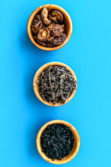 Chinese and Jupanese food cooking with mushrooms, spices, weeds in bowl on blue background top view copy space