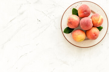 Summer fruits. Ripe red peaches on plate on white table top-down copy space