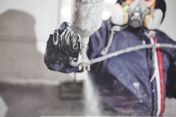 Close up image of carpenter painting with a paint spray gun