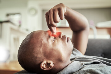 Naklejka premium Black man, headache and pain with stress on sofa for vertigo, dizziness or fatigue at home. Young African, male person or strain with red glow or migraine for anxiety, depression or pressure at house