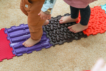 The child is walking on the puzzle sensory play orthopedic mats. Good for health and feet development. Funny play with a healthy benefit. 