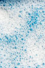 Background and pattern. White soap foam with bubbles, texture on blue tile background.