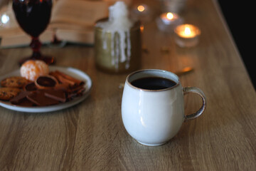 Books, lit candles, red wine, snacks and various deocration on the table. Dark academia or Halloween concept. Selective focus.