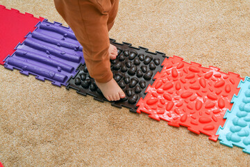 The child is walking on the puzzle sensory play orthopedic mats. Good for health and feet development. Funny play with a healthy benefit. 