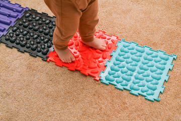 The child is walking on the puzzle sensory play orthopedic mats. Good for health and feet development. Funny play with a healthy benefit. 