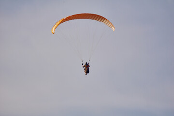 A paraglider flies over the sea and mountains during sunset. Extreme sports and adrenaline