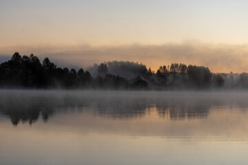 Blurred landscape with a lake in the morning fog, fog trailing over the lake