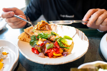 Close-up of a vibrant salad with mixed vegetables and grilled chicken, being eaten with a fork, served on a white plate. Perfect for healthy eating, food blogs, and culinary websites.