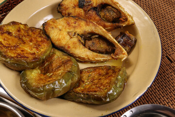 Bengali style fried hilsa ilish fish with fried brinjal Aubergine eggplant on rustic old metal tin plate