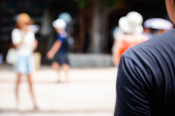 Obraz premium A blurry photo of a man and a woman in a park. The man is wearing a black shirt and the woman is wearing a white shirt. There are several other people in the background, some of them wearing hats