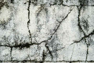 A wall with cracks and holes in it. The wall is white and has a rough texture. The cracks and holes give the wall a worn and aged appearance