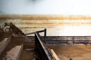A dirty staircase with a railing and a dirty wall. The railing is black and the wall is brown