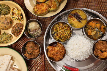 Bengali style thali spread verity cuisine hilsa fish vegetable beef mutton egg curry fry vorta mashed chicken liver sweet yogurt side dish served on rustic metal tin stainless steel plate small bowls