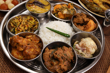 Bengali style thali spread verity cuisine hilsa fish vegetable beef mutton egg curry fry vorta mashed chicken liver sweet yogurt side dish served on rustic metal tin stainless steel plate small bowls