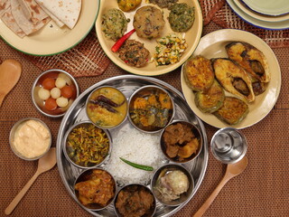 Bengali style thali spread verity cuisine hilsa fish vegetable beef mutton egg curry fry vorta mashed chicken liver sweet yogurt side dish served on rustic metal tin stainless steel plate small bowls