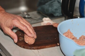 Male hands knead minced meat in the kitchen. A man prepares food from meat