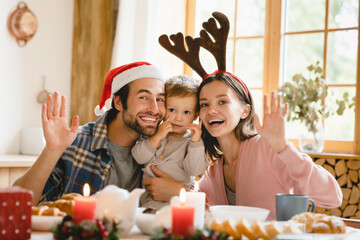 Happy young caucasian family of three parents and toddler celebrating New Year Christmas together...