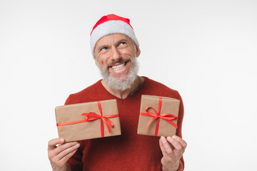 Pensive thoughtful caucasian mature middle-aged man in red Santa Claus hat holding Christmas New Year presents thinking isolated in white background. Sale offer discount