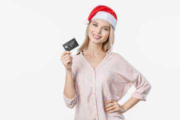 Smiling caucasian young woman in red Santa Claus hat doing shopping online paying with credit debit card for present and gifts, purchasing holiday and celebration over white background