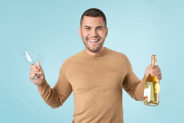Happy man holding goblets and champagne bottle sparkling wine standing over blue background looking at camera. Celebration birthday party new year christmas valentine day 8 march concept