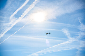 view of a bright blue sky with a flying airplane and condensation trails