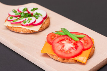 Different Cracker Sandwiches with Tomato, Cucumber, Radish and Cheese on Cutting Board. Easy Breakfast. Diet Food. Quick and Healthy Sandwiches. Crispbread with Tasty Filling. Healthy Dietary Snack