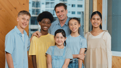 Happy teacher and diverse student standing while smilling to camera. Professional smart instructor with highschool children with mixed races in casual outfit pose at camera with cheerful. Edification.
