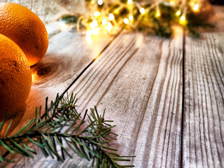 Festive decoration with bouquet and branches of spruce, bright glowing garlands, orange, burlap on wooden background. Decor for Christmas, New Year. Abstract texture, frame, place for text, copy space