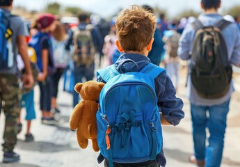 A boy with a blue backpack happily carries a teddy bear